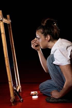 Young professional female mime in casual clothes applying foundation on face and looking in mirror while sitting on floor in dressing room JavierBallester_PippiClown_00001.jpg Copyright: xJavierxBallesterx Model Released