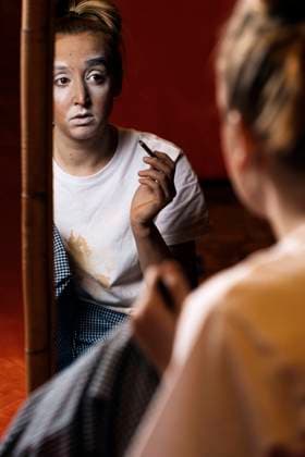 Young professional female mime in casual clothes painting the eyebrows and looking in mirror in dressing room JavierBallester_PippiClown_00005.jpg Copyright: xJavierxBallesterx Model Released