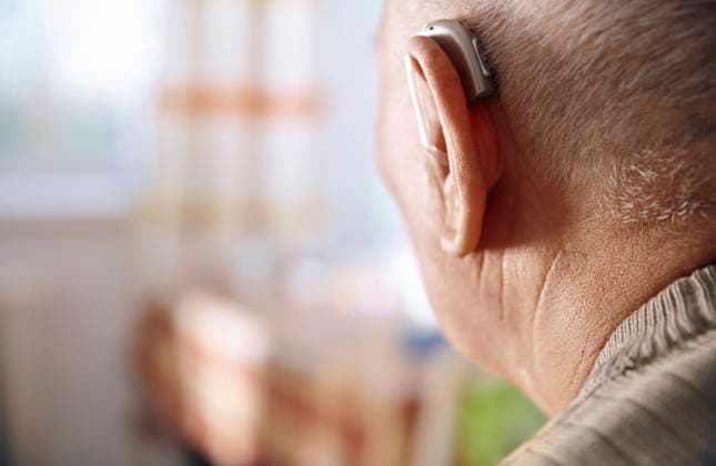 Ear of senior man with hearing aid model released, Symbolfoto, AZF00406