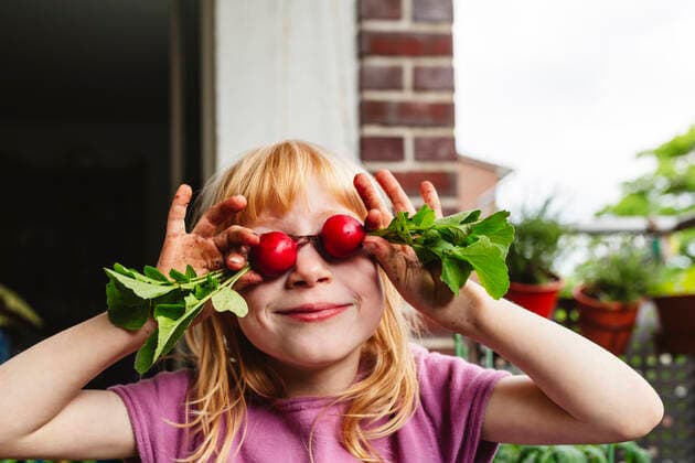 IMAGO Creative, Sommer, Food, Radieschen Smiling girl covering eyes with fresh radish on balcony model released, Symbolfoto property released, IHF00833