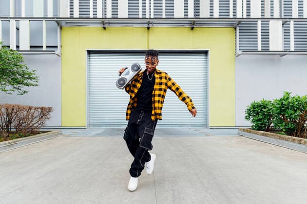 IMAGO Creative: 2022 Sport Favoriten Happy young man with boom box dancing in front of shutter model released, Symbolfoto, MEUF05681