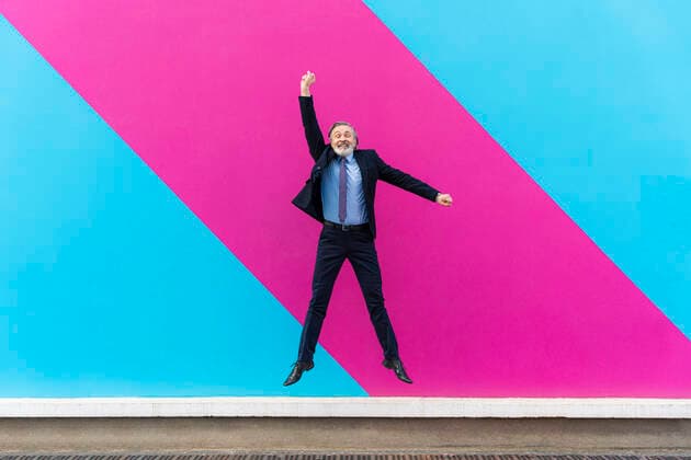 Creative Highlights Symbolbilder Happy mature businessman with hand raised jumping in front of pink and blue wall model released, Symbolfoto, OIPF02022