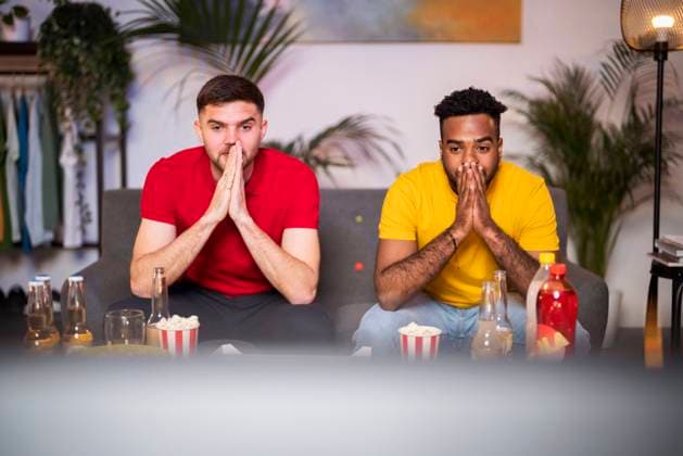 IMAGO Creative: FIFA WM 2022, Fußball Kultur Curious men with hands clasped watching football match at home model released, Symbolfoto property released, Florence Florence Italy SBAF00130