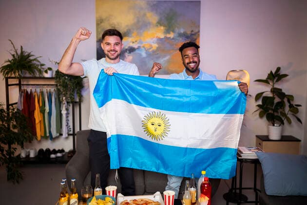 Cheerful young men gesturing fists standing with Argentinian flag at home model released, Symbolfoto property released, Florence Florence Italy SBAF00139