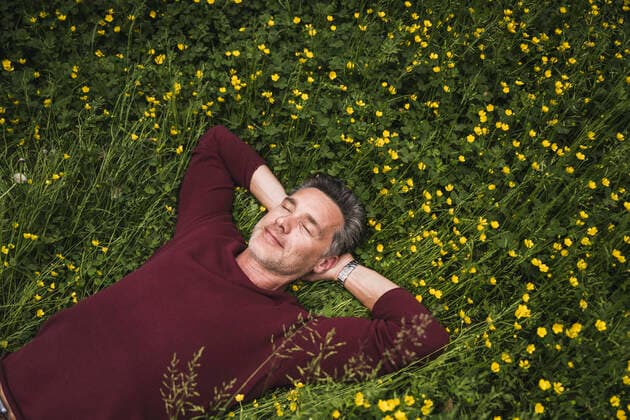 Creative Highlights Symbolbilder Smiling mature man lying on grass at park model released, Symbolfoto, UUF26251