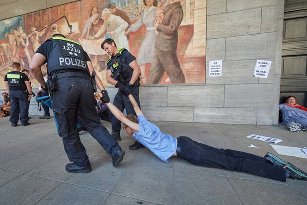 Bilder des Jahres 2022, News 06 Juni News Themen der Woche KW26 News Bilder des Tages Ein Demonstrant will sich nicht wegtragen lassen und wird an den Armen vom Haupteingang weggezogen waehrend Aktivist:innen der Klimaschutzinitiative Debt for Climate am 27.06.2022 Zugaenge des Bundesfinanzministeriums in Berlin blockieren (Foto). Anlaesslich des G7 Gipfels in Elmau kuendigten mehrere Gruppen globaler Klimagerechtigkeitsbewegungen Aktionen zivilen Ungehorsams an, um einen Schuldenerlass fuer Laender des globalen Suedens einzufordern. Die Aktion ist Teil der globalen Graswurzel-Initiative Debt for Climate , welche von Arbeits-, sozialen und Klima-Bewegungen des Globalen Suedens angefuehrt wird. (Siehe epd-Meldung vom 27.06.2022) Aktivist:innen der Klimaschutzinitiative Debt for Climate blockieren Zugaenge des Bundesfinanzmin Copyright: epd-bild ChristianxDitsch EDITORIAL USE ONLY