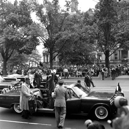 Arrival ceremonies for Dr. Manuel Prado Ugarteche, President of Peru 12:00PM. A large crowd watches as the Presidential motorcade arrives at Blair House, Washington, D.C., following arrival ceremonies for President Dr. Manuel Prado Ugarteche of Peru. President Prado (waving to the crowd) and President John F. Kennedy (partially hidden) stand in open presidential limousine (Lincoln-Mercury Continental convertible). Also pictured: Military Aide to President Kennedy, General Chester V. Clifton; Secret Service agents, Gerald Jerry Behn, Win Lawson, Art Godfrey, Dick Johnsen, and Clint Hill. Copyright: xpiemagsx