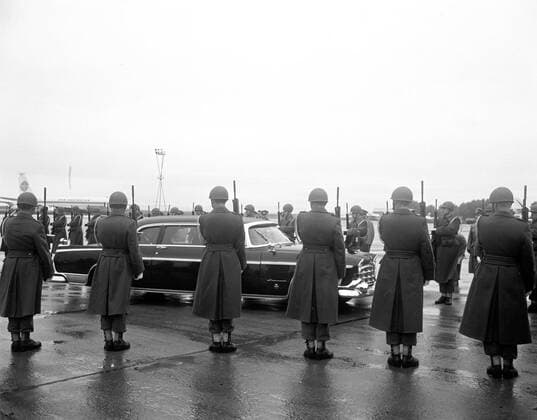 Trip to Europe: Arrival in Vienna, Austria 10:50AM; White House Army Signal Agency (WHASA) staff in Vienna. Austrian military honor guard and President John F. Kennedy in a car departing Schwechat Airport in Schwechat, Austria; the President visited Vienna for a summit with Soviet Union Premier Nikita Khrushchev. A Pan American World Airways airplane is visible in the background. Copyright: xpiemagsx
