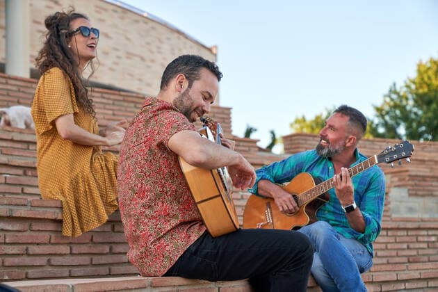 IMAGO Creative, Jahreszeit Sommer, Sommer in der Stadt From below content male musicians playing songs on acoustic guitars while sitting on steps with dog and woman on street, Model released JavierBermudez_RubenGuitarrist_36.jpg Copyright: xJavierxBermudezx MR