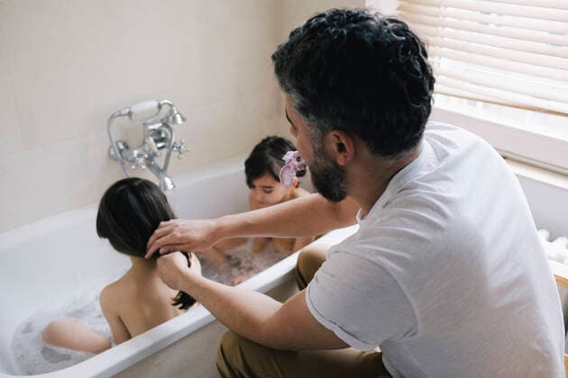 IMAGO Creative: Vaterschaft Father tying hair of daughter bathing with twin sister in bathtub at home Berlin, Germany, model released, property released Copyright: xMaskotx , MA92997 MA92997