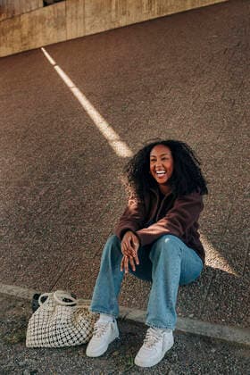 Creative Highlights Symbolbilder Happy young woman with bag sitting on slope at roadside Sweden, Stockholm, model released Copyright: xMaskotx , MA94591 MA94591