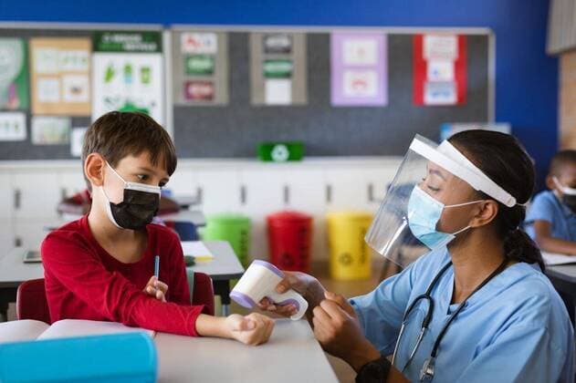 IMAGO Creative: Lokalhelden - Gesundheits- und Rettungskräfte Female health worker wearing face shield measuring temperature of a boy at elementary school Female health worker wearing face shield measuring temperature of a boy at elementary school. education back to school health safety during covid19 coronavirus pandemic., model released, , property released, Cape Town, South Africa, 17.04.2021, 1444569.jpg, people,female,health,worker,wearing,face shield,measuring,temperature,boy,elementary school,school education,back,safety,covid,coronavirus,pandemic,epidemic,virus,infection,quarantine,corona,flu,disease,outbreak,prevention,mask,protection,medical,ncov,illness,medicine,protective,influenza,healthcare,care,respiratory,face,shield,elementary,school,education Child,Boy,Male,Black,Caucasian,Mid Adult