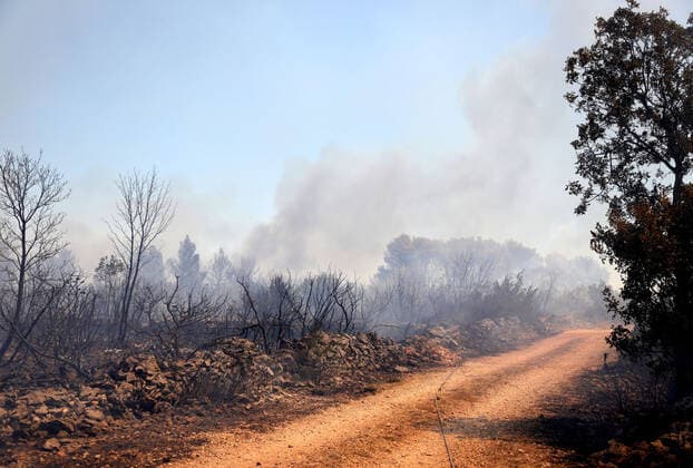 PXL_A fire near Vodice, Croatia Fire in an open area near the Velika Mrdakovica archaeological site in the Vodice hinterland, Croatia on July 13, 2022. About 30 firefighters with a dozen vehicles are on the ground, and two Canadairs joined the ground forces in extinguishing the fire. There are pine forests above, low vegetation, and endangered buildings. DuskoxJaramaz PIXSELL