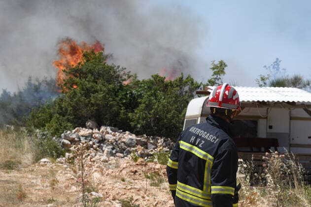 PXL_A fire near Vodice, Croatia Fire in an open area near the Velika Mrdakovica archaeological site in the Vodice hinterland, Croatia on July 13, 2022. About 30 firefighters with a dozen vehicles are on the ground, and two Canadairs joined the ground forces in extinguishing the fire. There are pine forests above, low vegetation, and endangered buildings. HrvojexJelavic PIXSELL