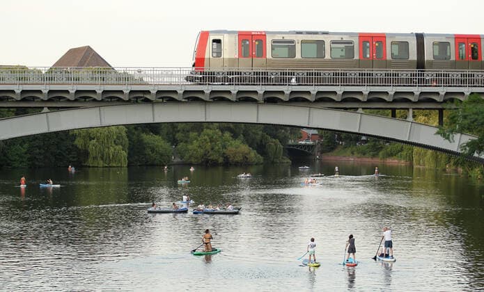 Passanten paddeln auf Stand-up Paddle Boards auf einem Alsterkanal unter einer Brücke entlang, die gerade von einer U-Bahn überquert wird. Am Dienstagabend herrschten in Hamburg bis in die späten Abendstunden noch Temperaturen bis an die 30 Grad. Hohenfelde Hamburg *** Passers-by paddle on stand up paddle boards along an Alster canal under a bridge, which is just crossed by a subway On Tuesday evening, temperatures in Hamburg were still up to 30 degrees until late in the evening Hohenfelde Hamburg