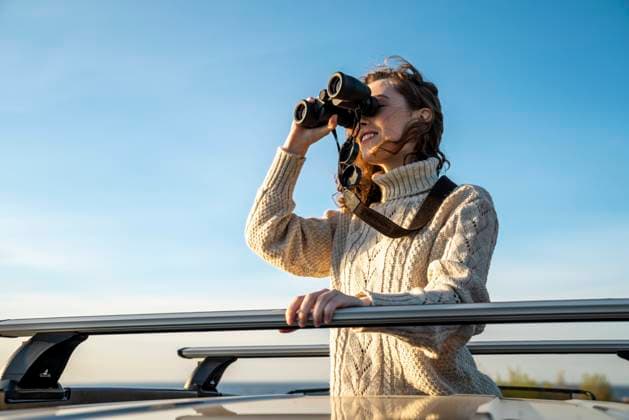 Happy young woman in warm clothing looking through binoculars model released, Symbolfoto, VPIF06362