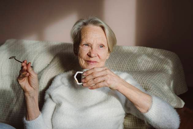 IMAGO Creative: Herbst, Gemütliches Zuhause Happy senior woman with coffee cup sitting at home model released, Symbolfoto property released, OSF00207