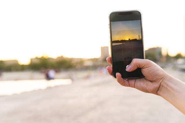Cropped hand of young woman photographing beach through smartphone during sunset DavidMunoz_JackVilaOlimpica_00105.jpg Copyright: xDavidxMunozx Model Released