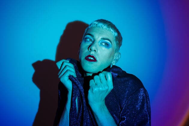 Creative Highlights Symbolbilder Gay man with eyeshadow posing and looking away against illuminated background, Model released JordiBataller_QueerReality_56.jpg Copyright: xJordixBatallerx MR