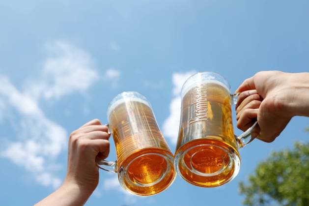 Zwei Bierglaeser mit Haenden stossen vor blauem Himmel in der Siegener Innenstadt an. Sommer im Siegerland am 04.08.2022 in Siegen Deutschland. *** Two beer glasses with hands toasting in front of blue sky in Siegen city center summer in Siegerland on 04 08 2022 in Siegen Germany