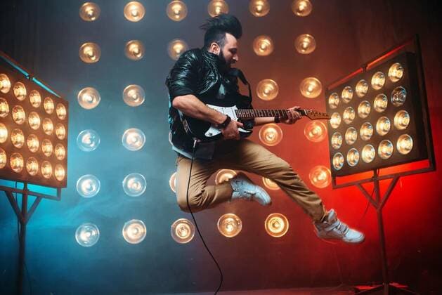  Male performer with electro guitar in a jump, Male performer with electro guitar in a jump on the stage with the decorations of lights. Music entertainment. Bearded musican song performing model released, Symbolfoto , 05.02.2020 02:30:45, Copyright: xNomadSoulx Panthermedia28060027.jpg