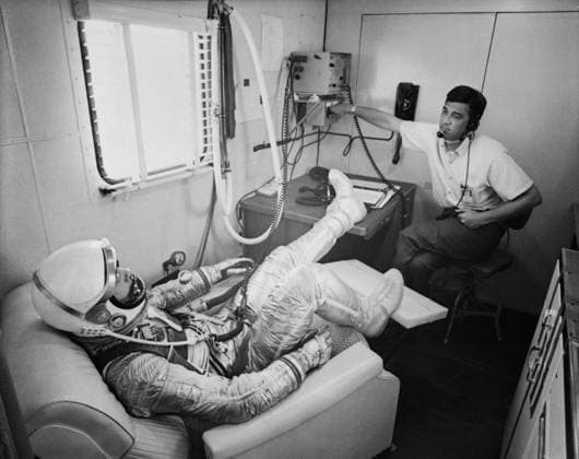 S61-02785 (5 May 1961) --- Astronaut Alan B. Shepard Jr. in his pressure suit is seated in a reclining chair while a technician checks communications equipment in his helmet. He is in the suiting trailer before the Mercury-Redstone 3 (MR-3) flight, the first American manned spaceflight. Copyright: xpiemagsx piemagsspace-54377 !ACHTUNG AUFNAHMEDATUM GESCHÄTZT!