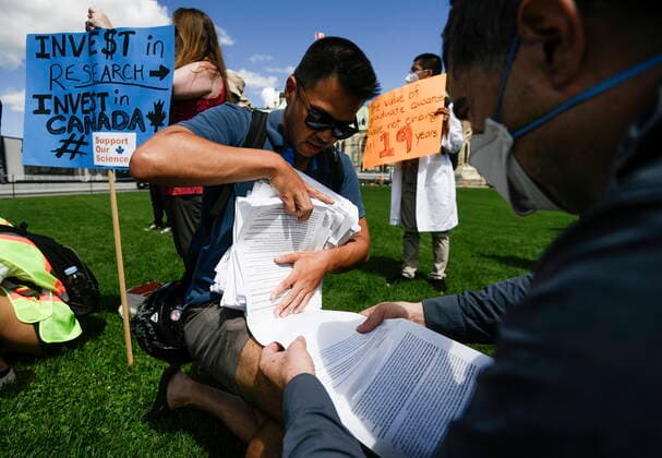 August 11, 2022, Ottawa, ON, CAN: Anh-Khoi Trinh, PhD candidate at McGill University and organizing member of the öÄuSupport Our ScienceöÄù rally, gathers up a 60 metre long petition with over 7,100 signatures, calling on the federal government to increase funding for graduate and post-doctoral scholars, on Parliament Hill in Ottawa, on Thursday, Aug. 11, 2022. Ottawa CAN - ZUMAc35_ 20220811_zaf_c35_040 Copyright: xJustinxTangx