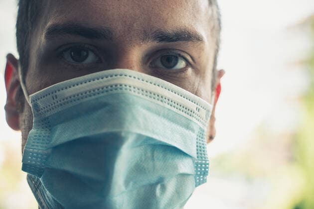 Riva, Italy - 15 August 2022: young man with medical op mask on summer vacation. Protection from Covid-19 Coronavirus Infection