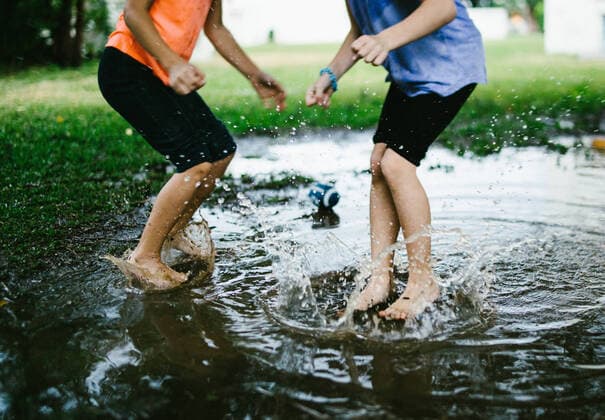 Creative Highlights Symbolbilder Two children jump into a rain puddle in green field Chatan, Okinawa, Japan CR_WVNP220816-1027851-01 ,model released, Symbolfoto