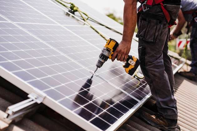 Electrician using power tool for installing solar panel on rooftop model released, Symbolfoto property released, EBBF05711