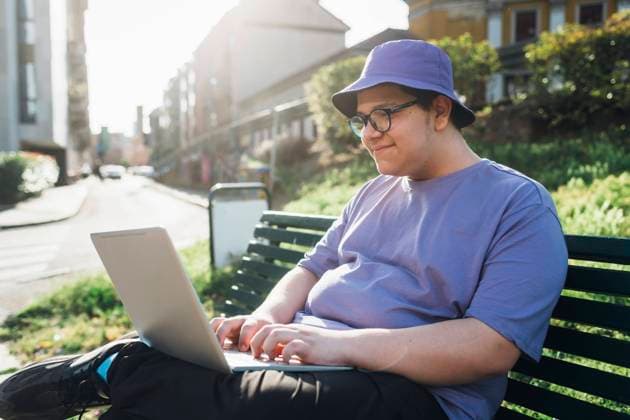 Smiling teenage boy using laptop on bench in park model released, Symbolfoto, MEUF07370