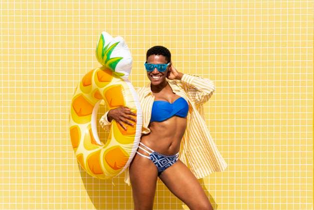 Cheerful woman with inflatable ring in front of yellow wall model released, Symbolfoto, OIPF02142