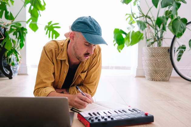 Man with piano and laptop writing in book at home model released, Symbolfoto property released, ASGF02604