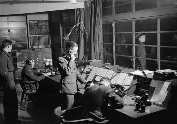 Royal Air Force Bomber Command, 1942-1945. The Officer of the Watch in the Watch Office at Snaith, Yorkshire, guiding Handley Page Halifaxes of No. 51 Squadron RAF back to base after a night raid on Nuremberg. The Station Commander of Snaith, Group Captain N H Fresson, can be seen waiting outside on the balcony of the Control Tower. Copyright: xpiemagsx airministryww2pie13032022-1799 !ACHTUNG AUFNAHMEDATUM GESCHÄTZT!