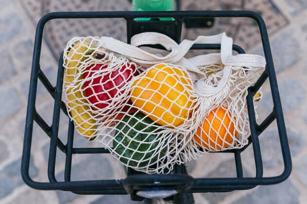 From above of eco friendly mesh bag with fresh fruits and vegetables placed in metal basket of bike parked on street in city, Model released DavidMunoz_AlejandroEco_36 Copyright: xDavidxMunozx MR