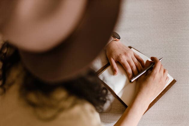 Relaxed young woman writing in a notebook at home while sitting on couch, Model released MarioCalvo_GirlatHome_22 Copyright: xMarioxCalvox MR