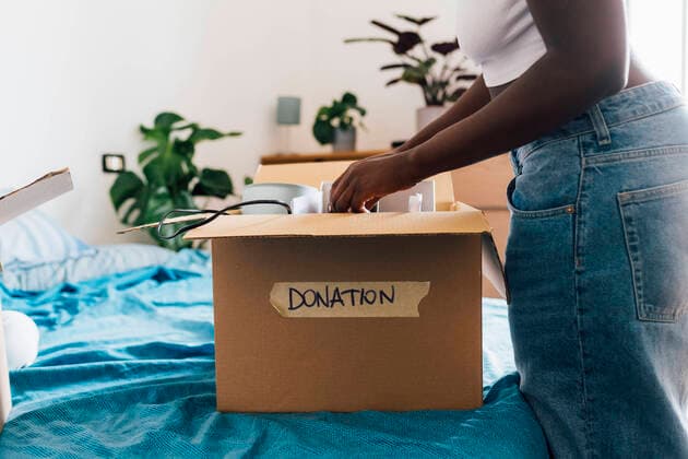Woman packing donation box on bed at home model released, Symbolfoto property released, MEUF07893
