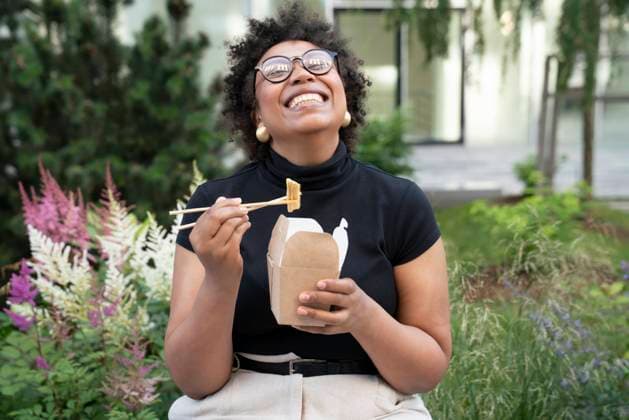 Happy young businesswoman with chopsticks and take out food sitting in office park model released, Symbolfoto, VPIF06975