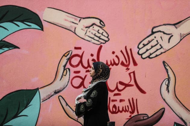 Bilder des Jahres 2022, News 08 August News Themen der Woche KW35 News Bilder des Tages Daily Life In Gaza City A Palestinian woman carrying her child walks in front of a mural at al-Shati camp for Palestinian refugees in Gaza City, on August 29, 2022. Gaza Palestine  Copyright: xMajdixFathix originalFilename: fathi-notitle220829_npzKy.jpg