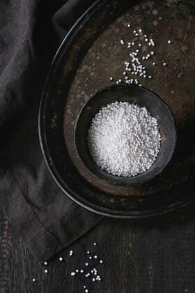 IMAGO Creative, Food, Tapioka Uncooked tapioca pearls Healthy superfood. Uncooked tapioca pearls in balck iron bowl on vintage iron tray over dark old wooden background with textile napkin. Top view. Copyright: xNatashaxBreenx xThexPicturexPantryx 08NB616-19