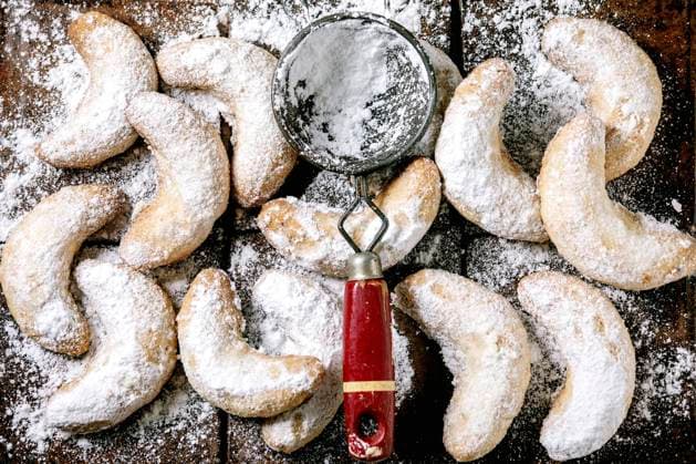 Christmas shortcrust cookies vanilla crescents with icing sugar. Top view Homemade traditional Christmas shortcrust cookies vanilla crescents with icing sugar and vintage sieve over dark ceramic tile background. Top view Copyright: xNatashaxBreenx NB221120-6