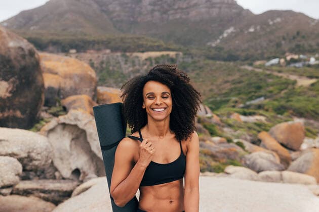 Creative Highlights Symbolbilder Portrait of a smiling fit woman with closed eyes holding a mat while standing by mountains in valley Copyright: xArtemxVarnitsinxArtemxVarnitsinx