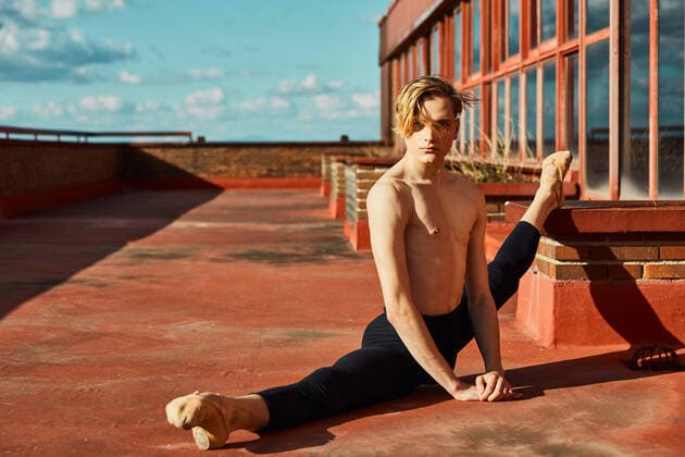 IMAGO Creative: 2022 Sport Favoriten Creative Highlights Symbolbilder Concentrated young blond slender ballet dancer in black leotard and pointe shoes performing transverse twine on roof of building in sunny day and looking at camera, Model released CienXCienStudio_DancerBoy_55 Copyright: xCienxXxCienxStudiox MR