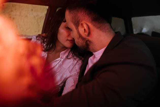 Newlywed couple kissing inside a car with red neon lights and bouquet flowers in foreground out of focus., Model released DavidBarrera_WeddingCouple_21 Copyright: xDavidxBarrerax MR