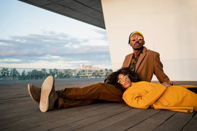 Loving black man with dreadlocks sitting with charming girlfriend lying down on his lap in bright coat on wooden floor on the street, Model released RafaCortes_AlphaDayanis_100 Copyright: xRafaxCortesx MR