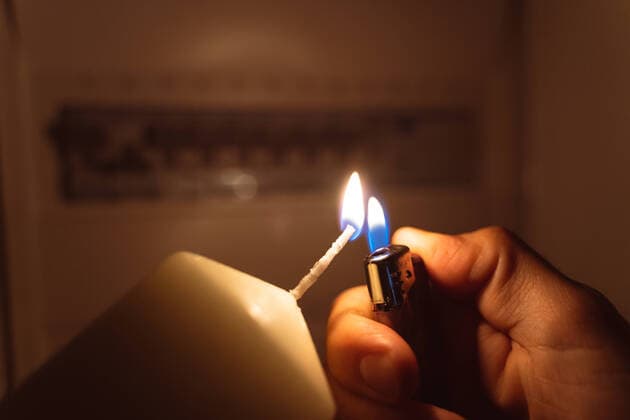 Bavaria, Germany - 25 September 2022: Power failure in the apartment, man lights with candlelight and checks the fuse box. electricity, power outage, blackout concept *** Stromausfall in der Wohnung, Mann leuchtet mit Kerzenlicht und überprüft den Sicherungskasten. Elektrizität, Strom Ausfall, Blackout Konzept