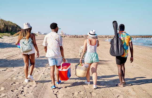 Full body back view of unrecognizable multiracial men and women in sunglasses and hat strolling on sand against cloudless blue sky while spending time on beach on summer day, Model released AdalbertoRodriguez_ID644_23524_006 Copyright: xAdalbertoxRodriguezx MR