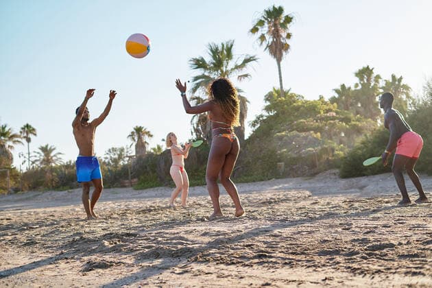Low angle of diverse men and women tossing ball and playing beach tennis while spending summer weekend day on sandy seashore together, Model released AdalbertoRodriguez_ID644_23634_068 Copyright: xAdalbertoxRodriguezx MR