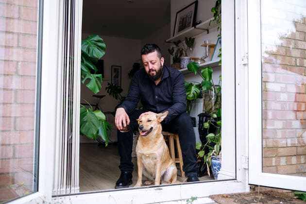 Depressed man holding drink stroking dog sitting on stool at doorway model released, Symbolfoto property released, ASGF02720