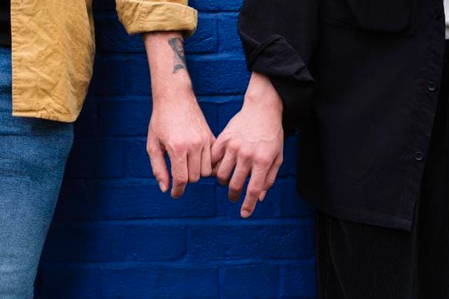 Gay couple holding hands standing in front of blue wall model released, Symbolfoto property released, ASGF02848